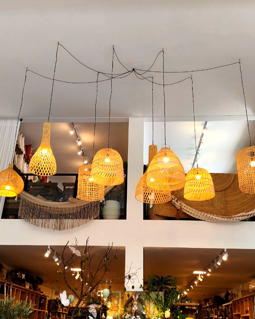 Conjunto de pendentes de palha acesos no pé-direito duplo de uma loja